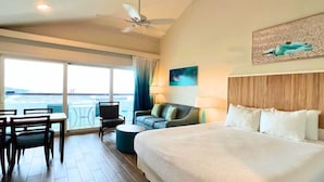 A hotel room with a large bed, a desk, a chair, a sofa, and a view of the sea. - Bluebeard's Castle Resort (Charlotte Amalie)