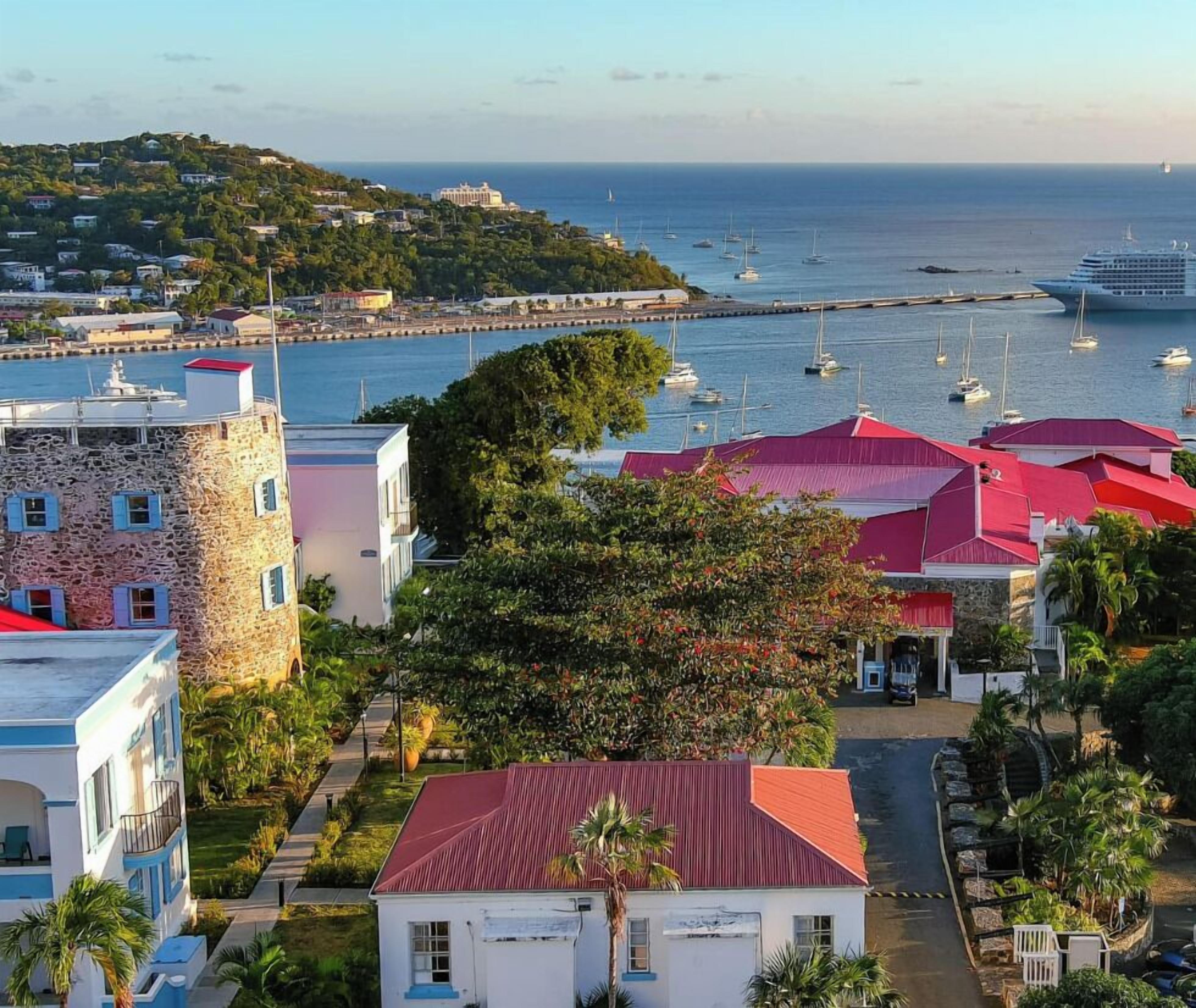 A coastal town with a marina, stone buildings, and a large cruise ship docked.