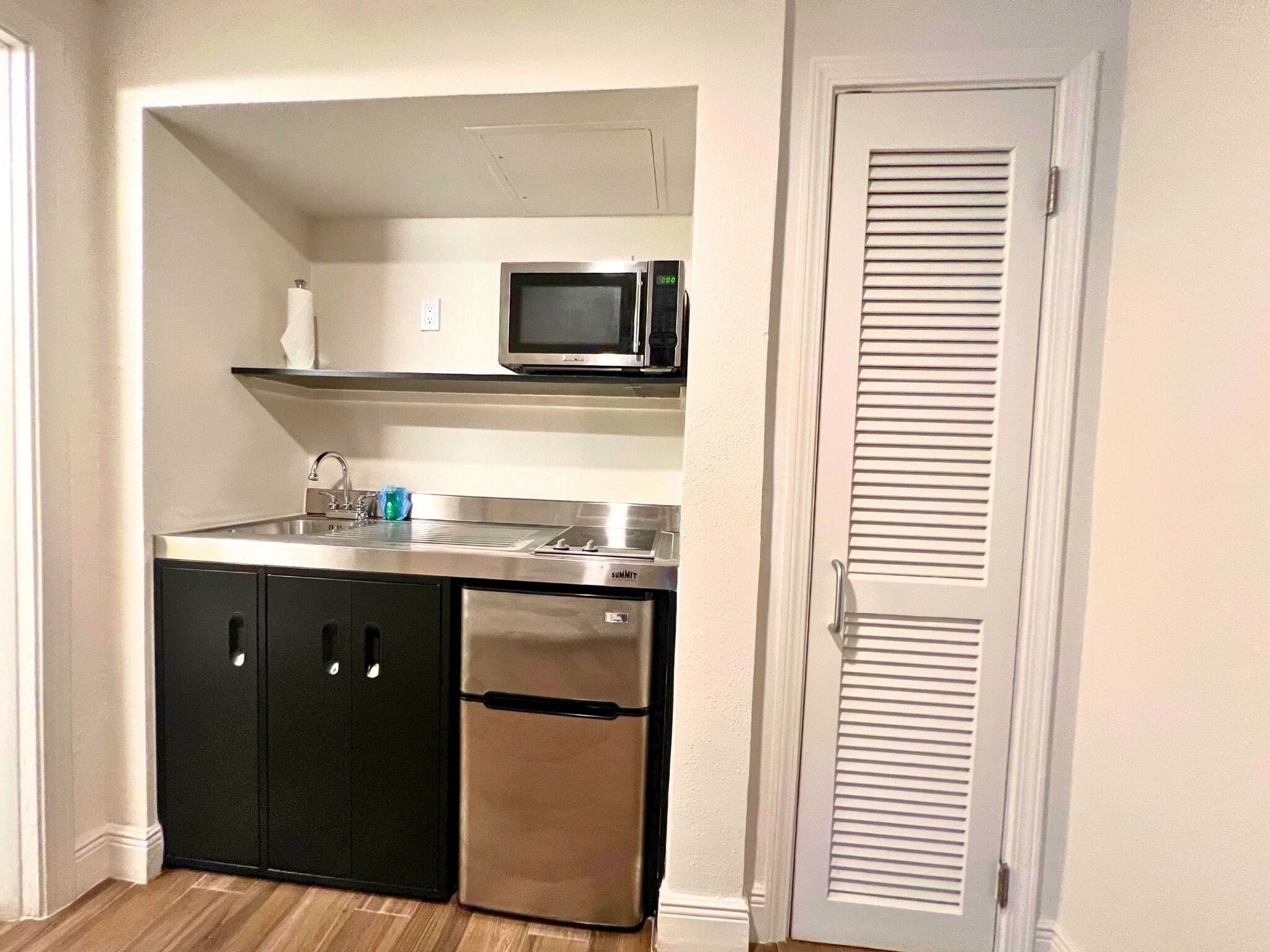 Una cocina compacta con microondas, fregadero y lavavajillas.