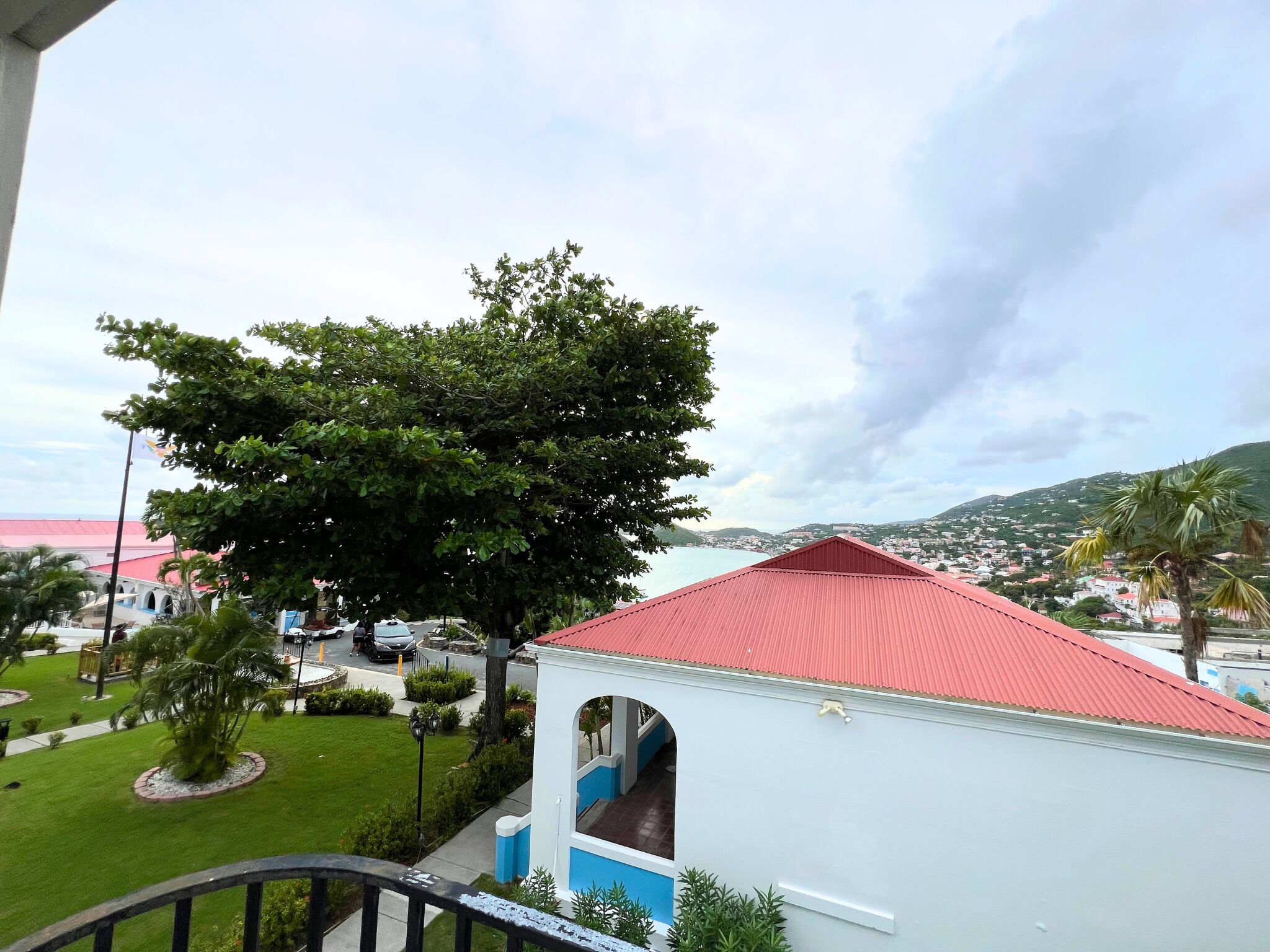Vista de una zona costera con un edificio de techo rojo y un gran árbol en primer plano.