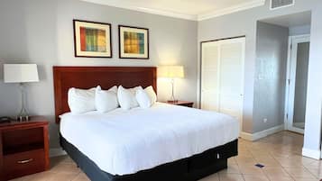 A hotel room with a large bed, two bedside lamps, a wooden headboard, and two framed artworks on the wall.