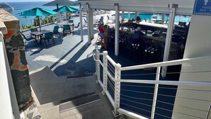 A sunlit outdoor seating area with umbrellas, a pool, and a view of the sea. - Bluebeard's Castle Resort (Charlotte Amalie)