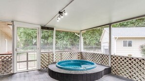 A covered outdoor area with a hot tub, wooden deck, and a view of a house through a screened door. - Nancy`s Ranch + hot tub (Derby)