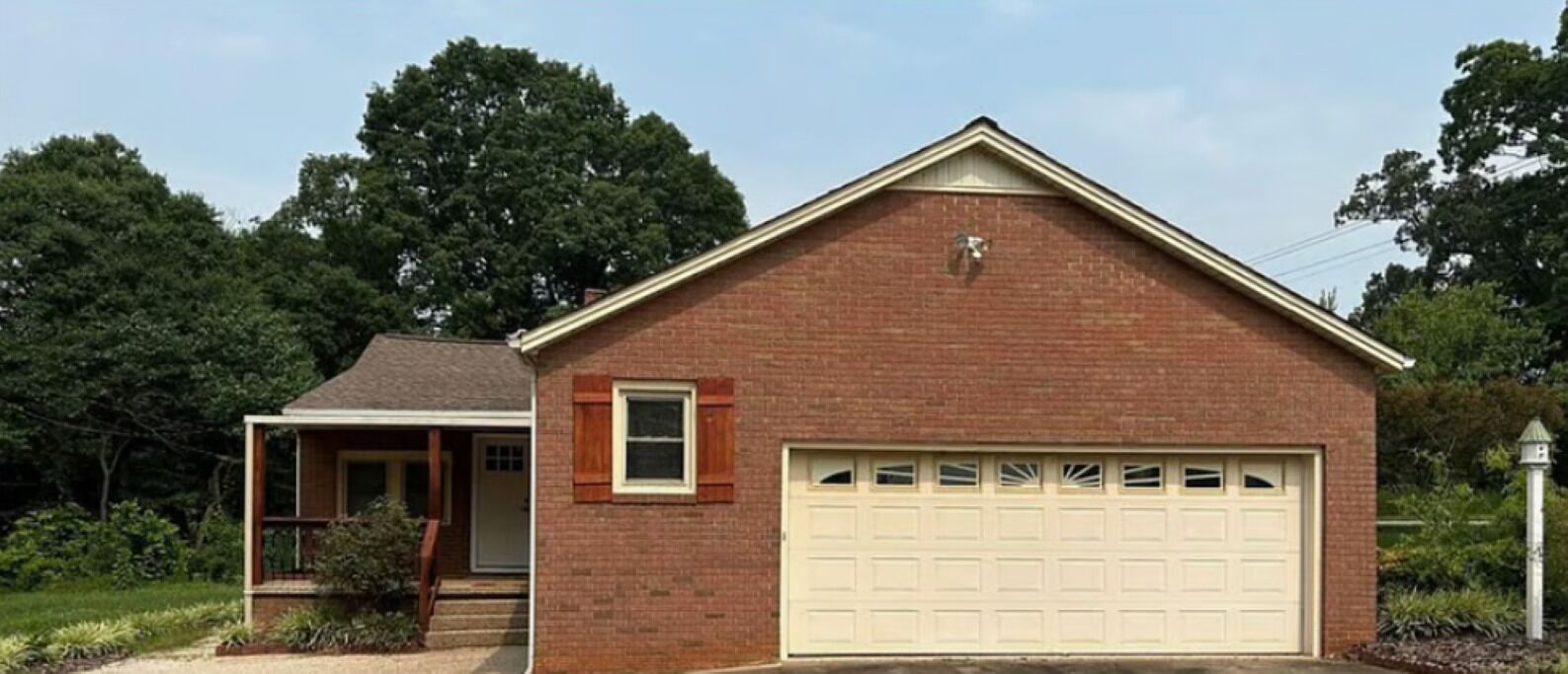 A single-story brick house with a garage, a small porch, and a well-maintained lawn.