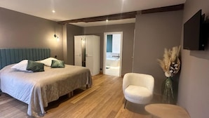 Een moderne slaapkamer met een bed, een stoel, een klein tafeltje en een kledingkast.
