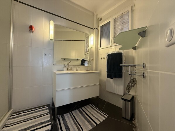 A bathroom with a white sink, mirror, and towel rack. There is a striped rug on the floor. - 2 BR Apartment in the Center of Cannes - 2305 (Cannes)