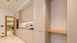 Una cucina moderna con mobili bianchi, forno integrato e ripiano in legno.