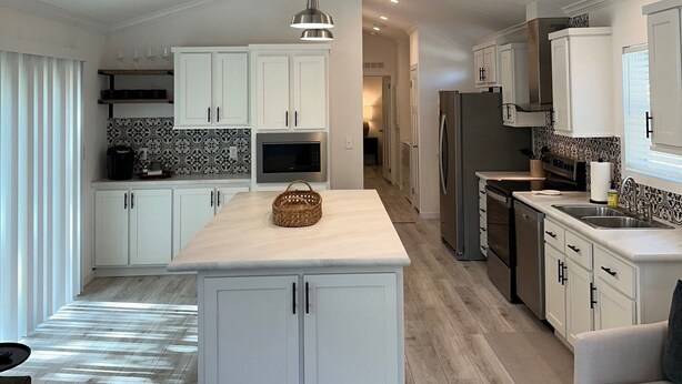 A modern kitchen with white cabinetry, a central island, and a ceiling fan. - Brand New Lake Cabin!  1 Mile from Buzzard Roost Boat Dock (Mountain Home)
