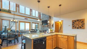 Una cocina amplia con lavavajillas, armarios de madera y una isla grande. Hay varias ventanas y vistas al exterior.
