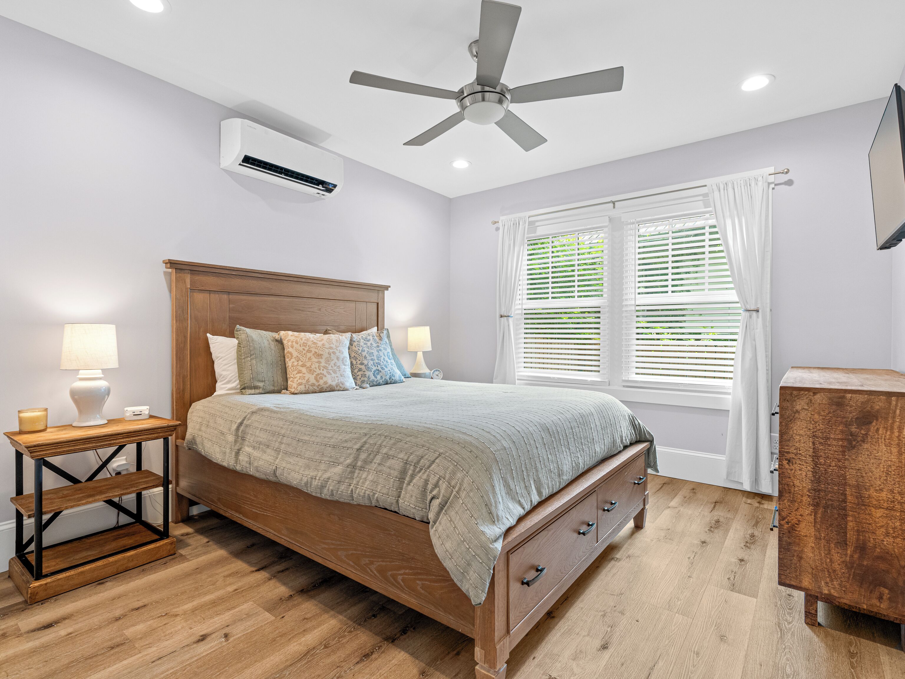 Una camera da letto con un letto in legno, comodini con lampade, una ventola a soffitto e una finestra con tende.