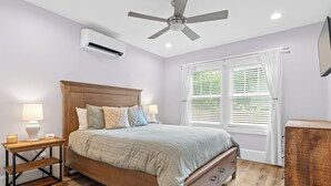 A bedroom with a wooden bed, bedside tables with lamps, a ceiling fan, and a window with blinds.