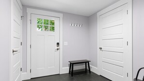 A hallway with two white doors, a small bench, and a coat rack.
