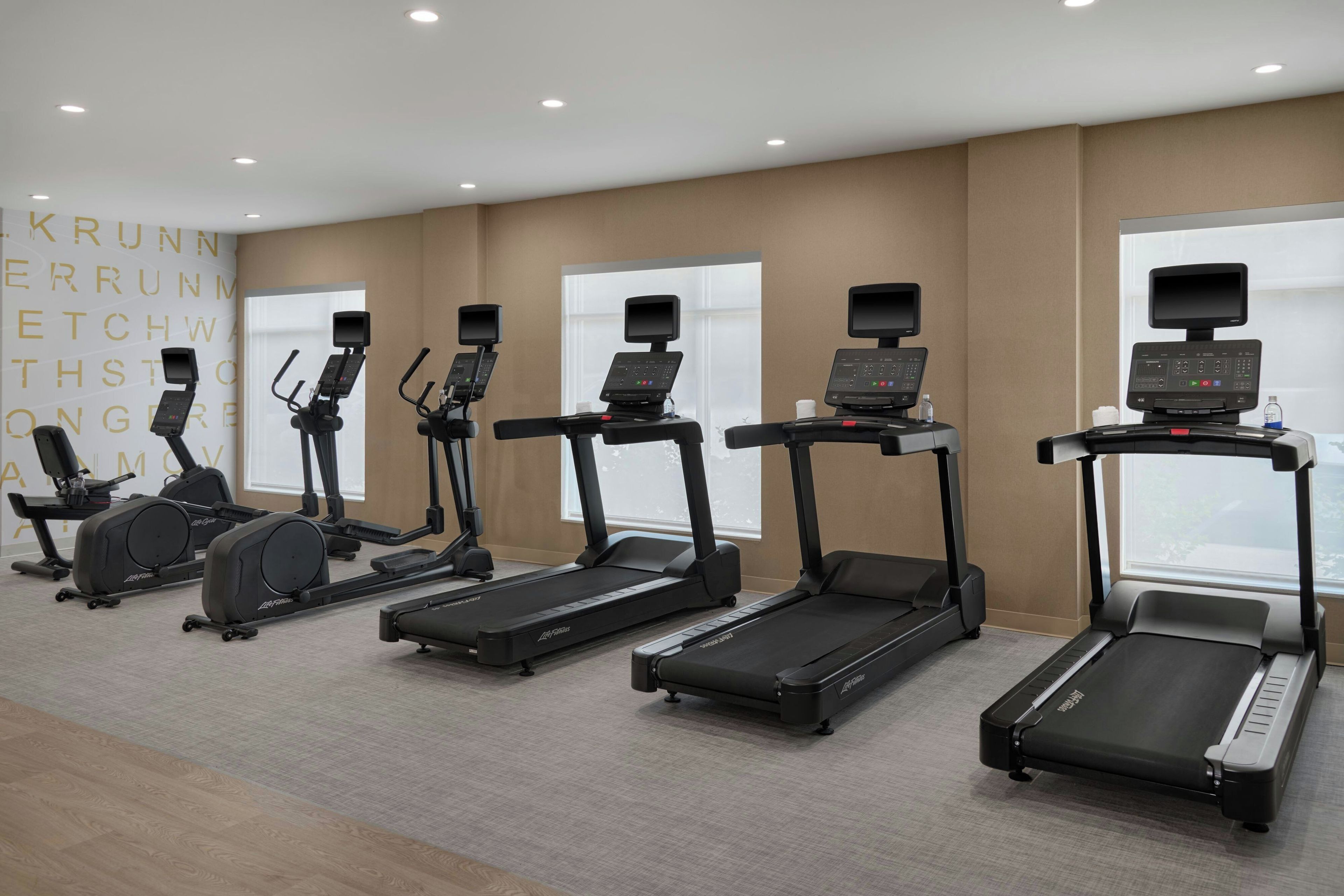 A fitness room with multiple treadmills, stationary bikes, and elliptical machines.
