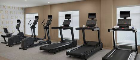 A fitness room with multiple treadmills, stationary bikes, and elliptical machines.