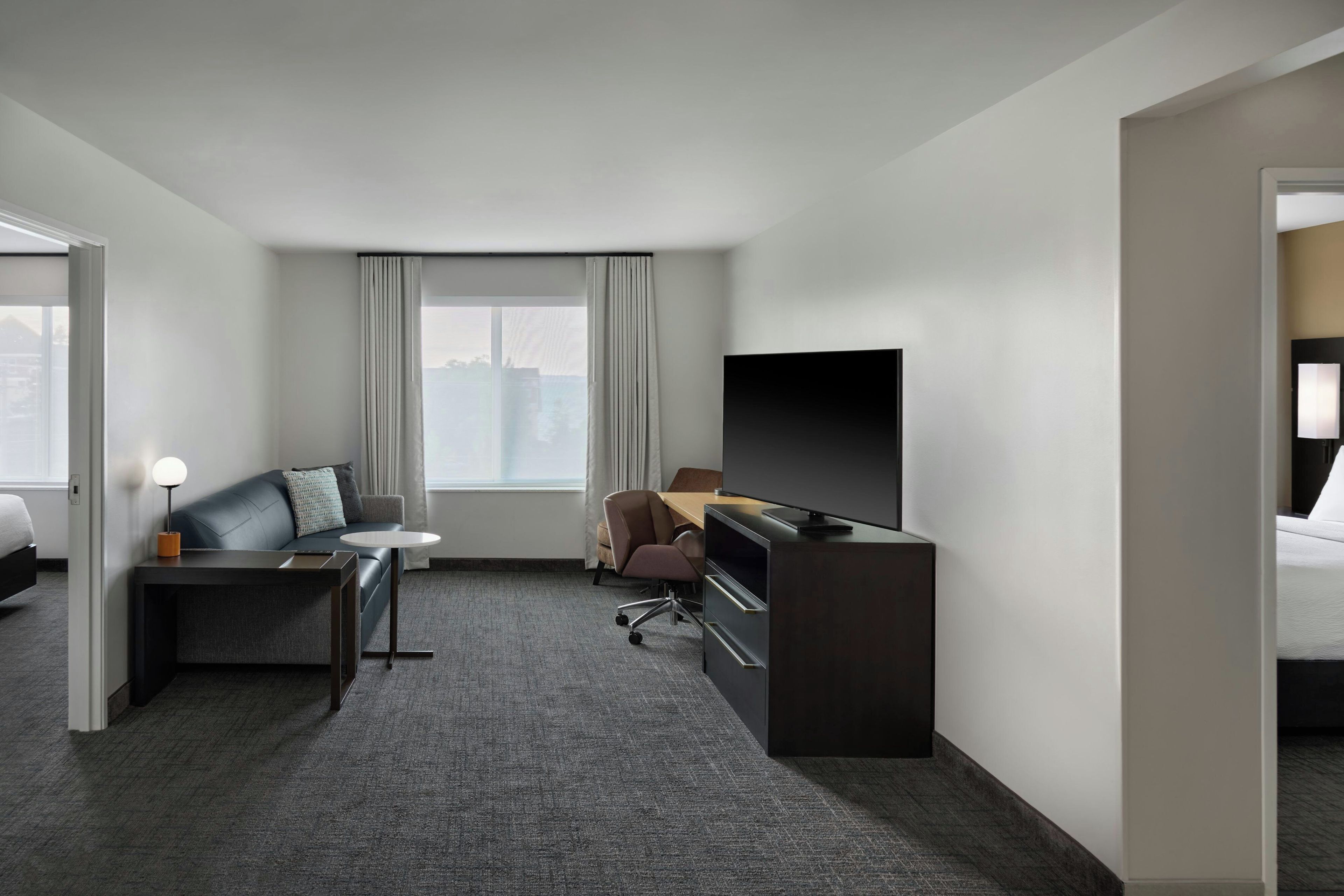 A hotel room with a bed, a desk, a chair, a television, and a window with curtains.