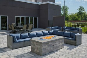 Un patio exterior con una chimenea integrada, zona de estar y comedor.