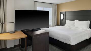 Una habitación de hotel con una cama, televisión, mesita de noche y lámpara.
