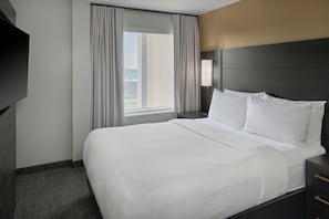 A hotel room with a large bed, a nightstand, a lamp, and a window with curtains. - Residence Inn By Marriott Traverse City (Traverse City)