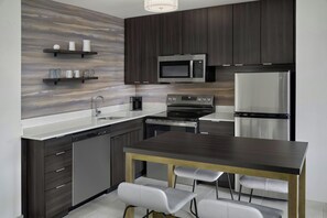 Una cocina moderna con armarios de madera oscura, electrodomésticos de acero inoxidable y una isla central con taburetes de bar.