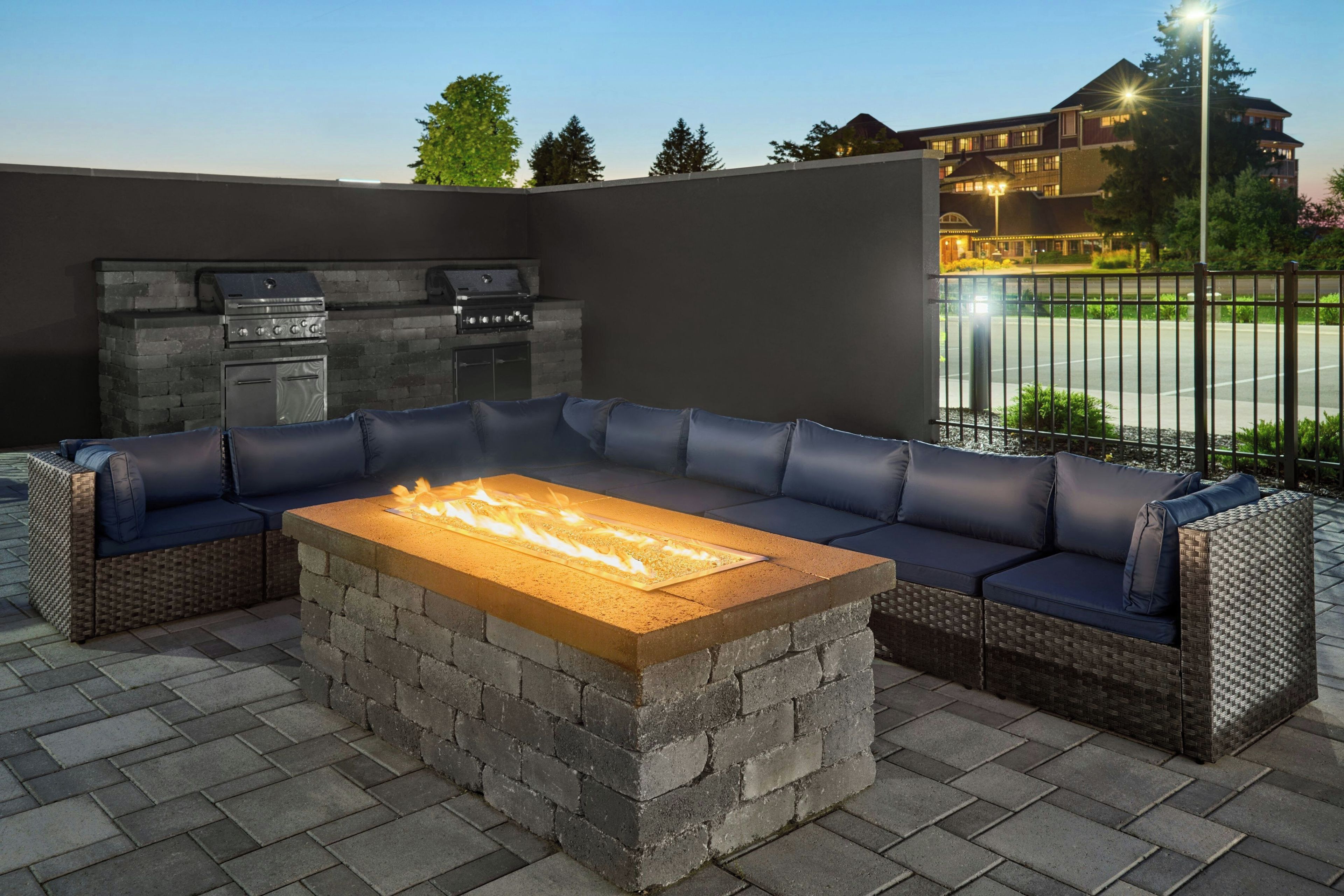 An outdoor patio with a built-in fire feature, a large cushioned seating area, and a stone fireplace.