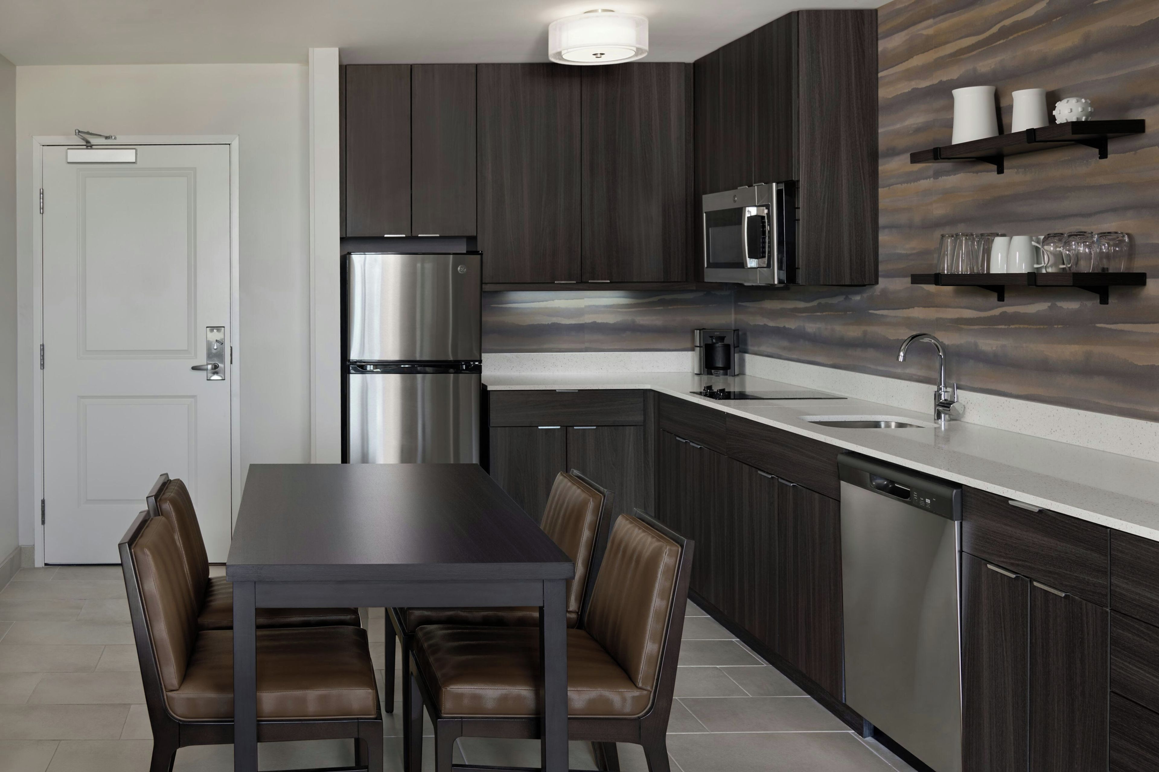 Una cocina moderna con armarios de madera oscura, electrodomésticos de acero inoxidable y encimera blanca.