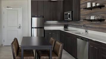 Una cocina moderna con armarios de madera oscura, electrodomésticos de acero inoxidable y encimera blanca.