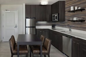 A modern kitchen with dark wood cabinets, stainless steel appliances, and a white countertop. - Residence Inn By Marriott Traverse City (Traverse City)