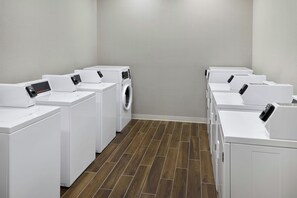 Un cuarto de lavandería con varias lavadoras y secadoras dispuestas en filas.