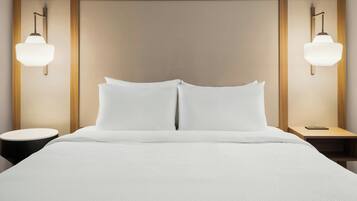A hotel room with a large bed, two bedside tables, and wall-mounted lamps.