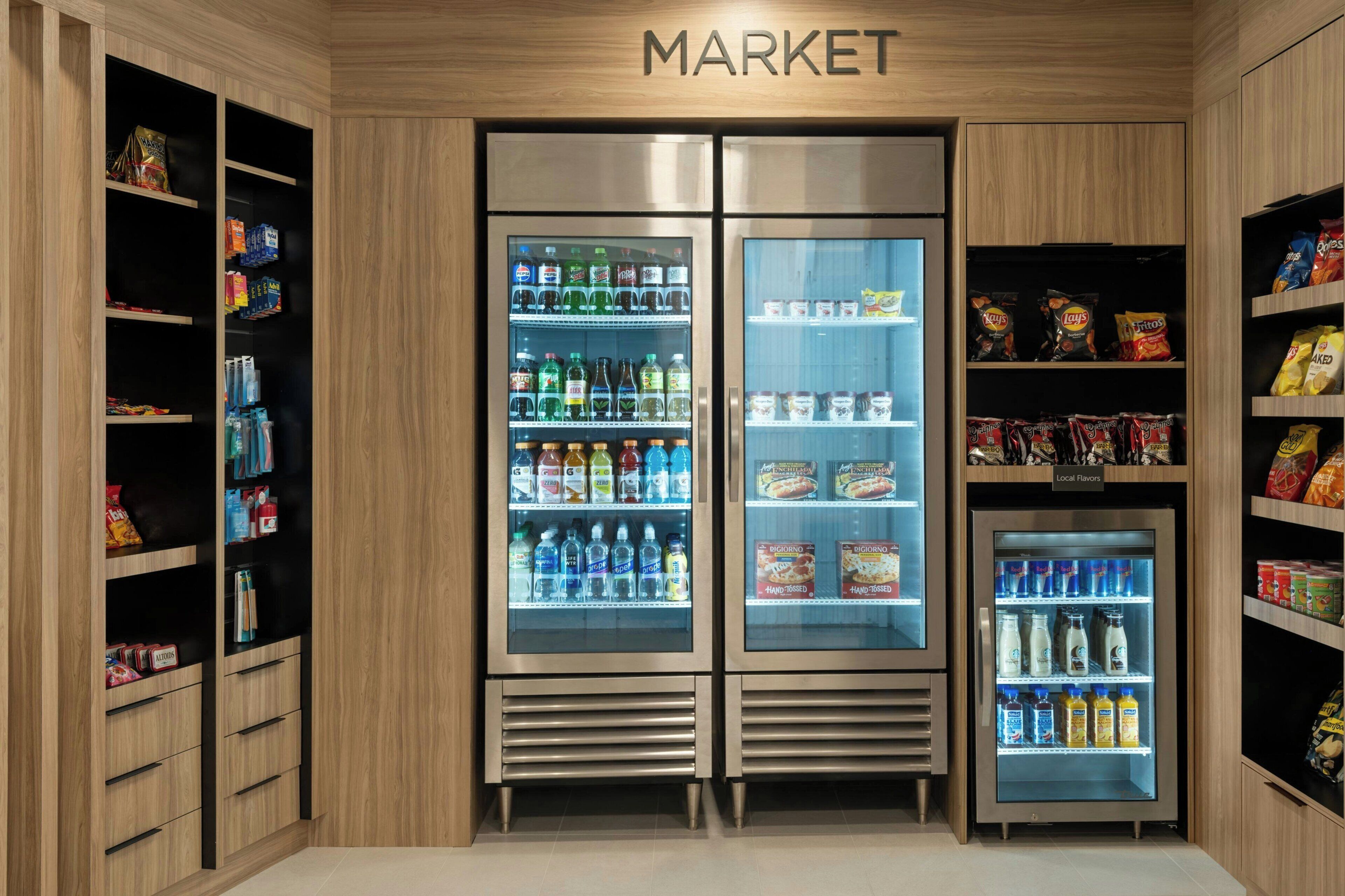 Un espace commercial où l’on trouve des étagères réfrigérées remplies de boissons et d’en-cas.