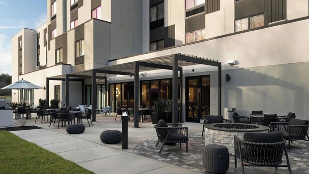 A modern hotel exterior with outdoor seating, a covered patio, and a stone fireplace. - Fairfield By Marriott Inn & Suites Corbin (Corbin)