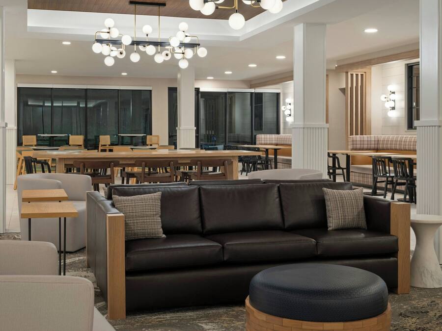 A modern interior with a leather sofa, wooden tables, and a chandelier.