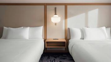 A hotel room with two beds, a nightstand, a wall-mounted light, and a patterned rug.