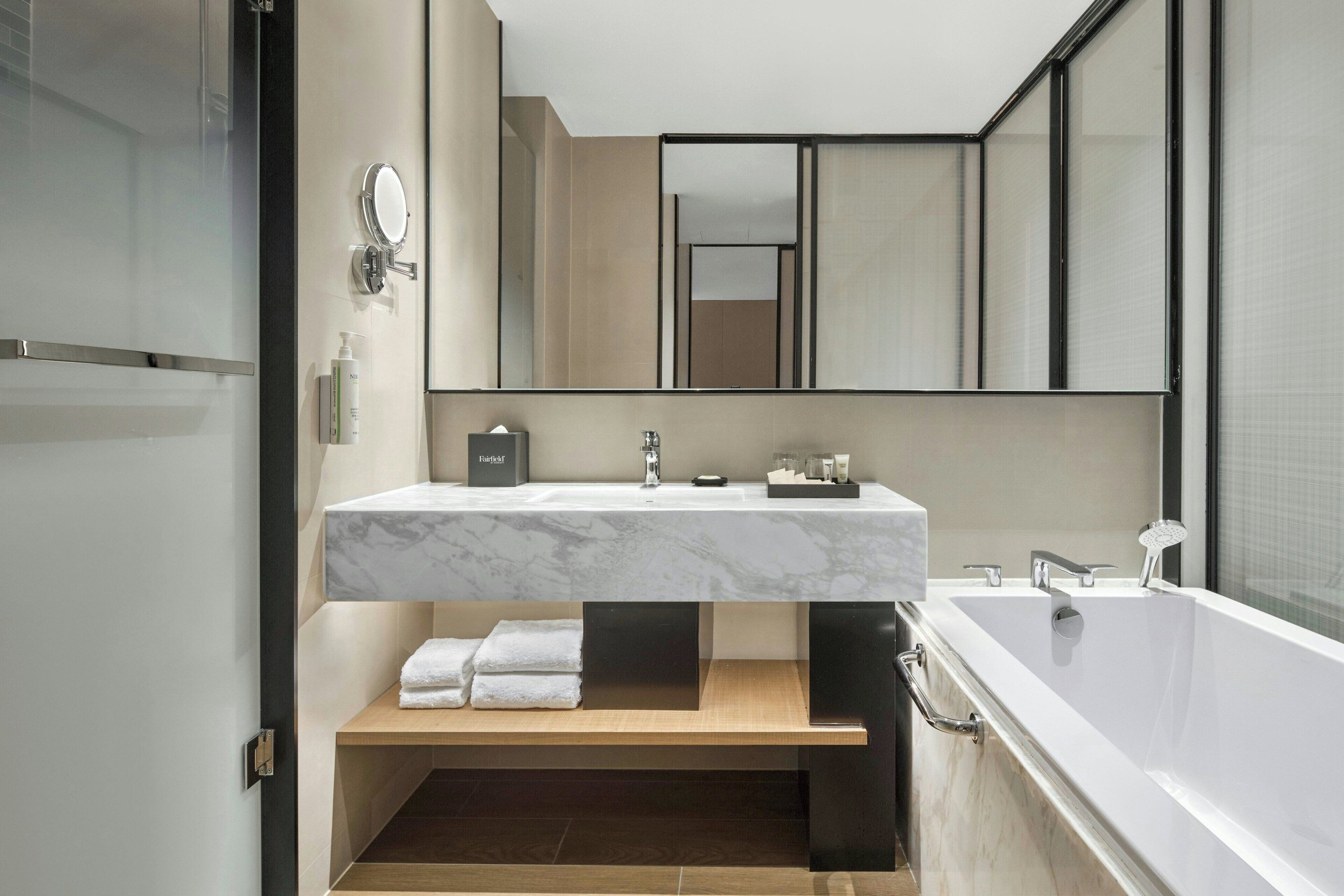 Un baño moderno con lavamanos de mármol, un espejo grande y una bañera.