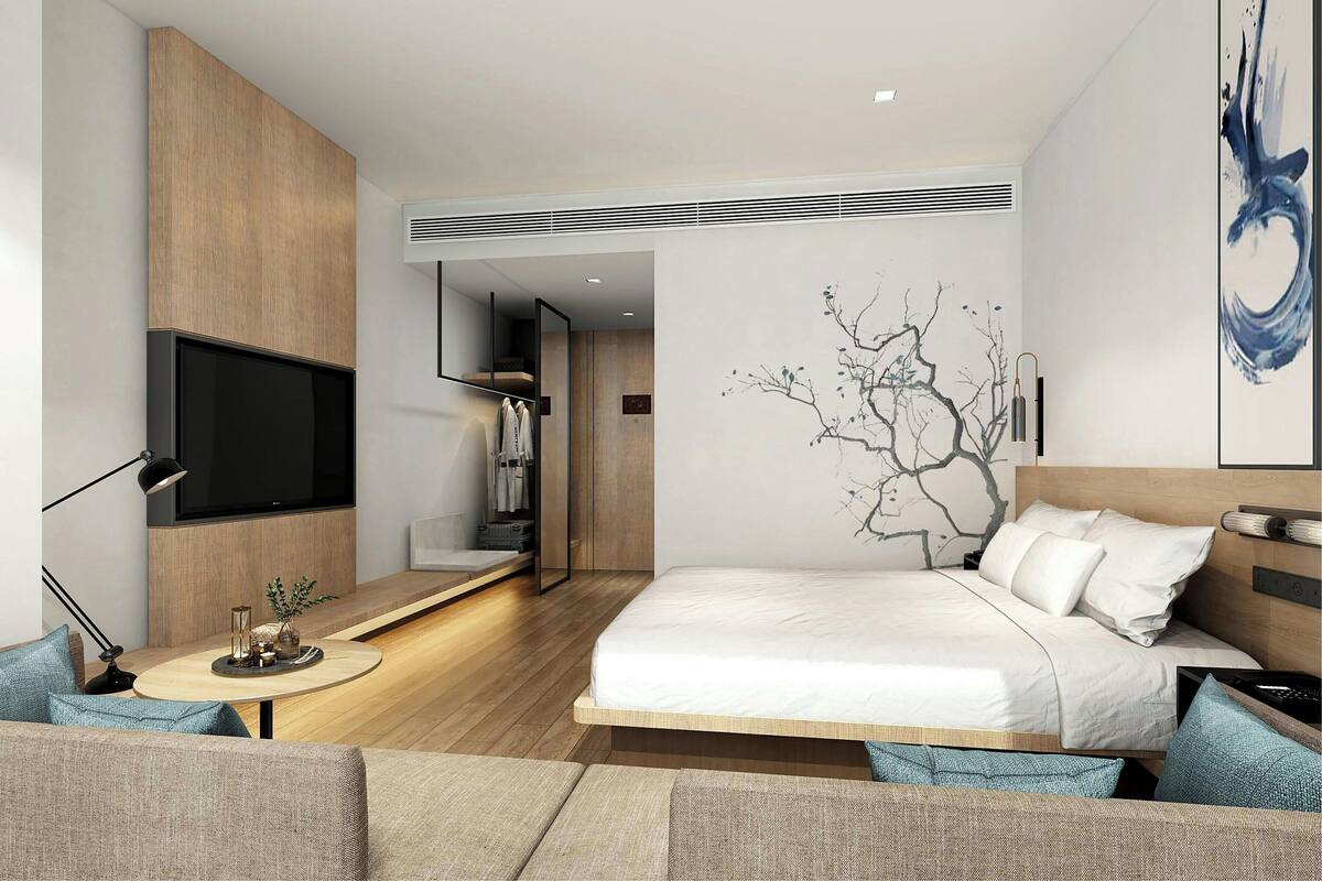 Une chambre d’hôtel moderne équipée d’un lit, d’une télévision, d’un bureau avec une lampe et d’une œuvre d’art murale.