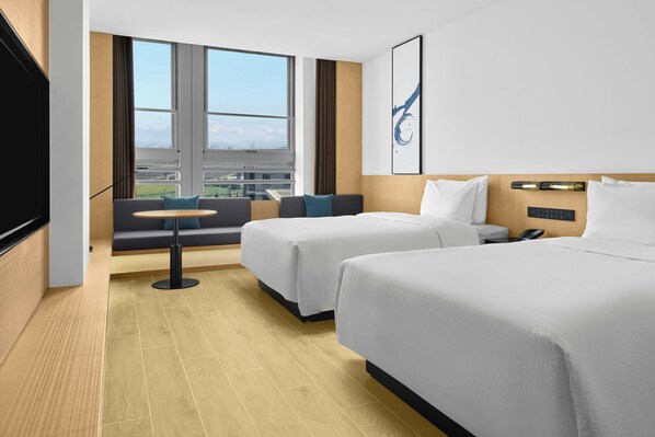 A hotel room with two beds, a sofa, a small table, and a large window offering a city view. - Fairfield By Marriott Yancheng Dafeng (Yancheng)