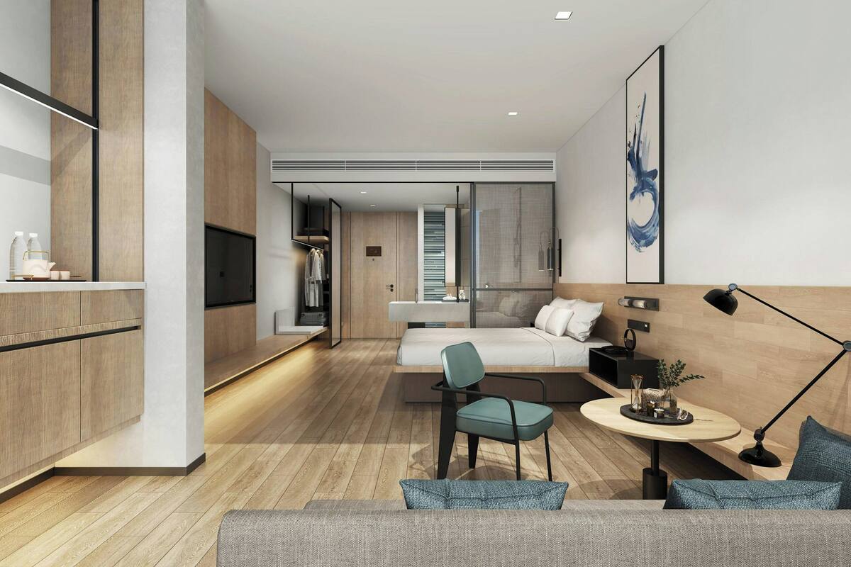 Une chambre d’hôtel moderne comprenant un lit, un coin salon avec une table, une télévision et une armoire.