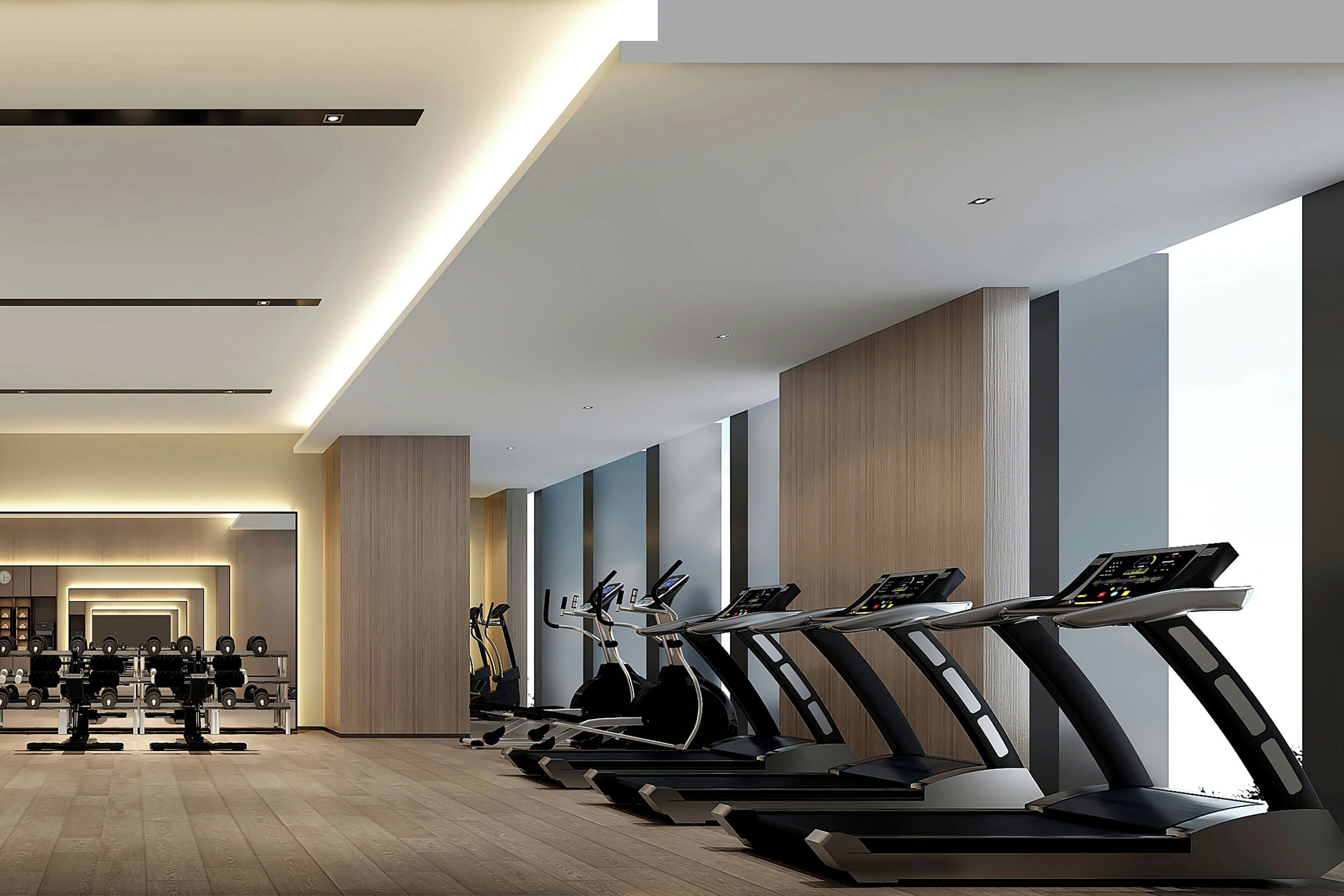 Et moderne fitnesscenter med flere løbebånd stillet op langs en væg med store vinduer.