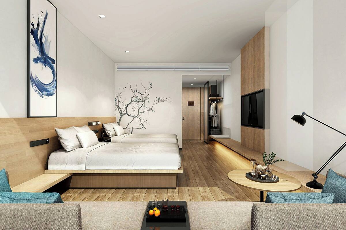 Une chambre d’hôtel moderne équipée d’un lit, d’un canapé, d’une petite table avec des boissons et d’une télévision.