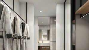 Un couloir d’hôtel moderne avec un banc en bois, un portant à vêtements et un mur miroitant.