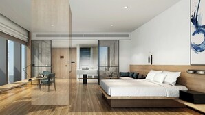 Une chambre moderne avec un grand lit, un bureau et une chaise. On peut apercevoir la salle de bain à travers une porte en verre.