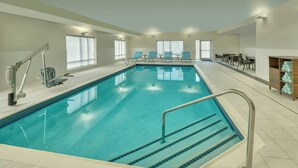 Una piscina interior con vista despejada, un puesto de socorrista y sillones de descanso.