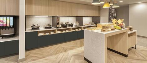 A modern kitchen with wooden cabinets, a central island, and a digital menu display.