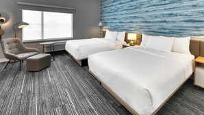 Habitación de hotel con una cama grande, una silla, un escritorio y vistas al exterior.
