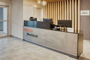 Un mostrador de recepción con un letrero que dice 'HELLO Woodstock', un teléfono y un letrero en la pared que dice 'MARRIOTT BONVOY'.