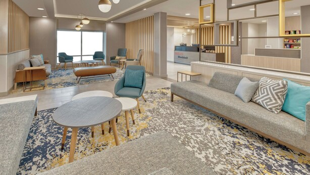 Un moderno vestíbulo de hotel con mostrador de recepción, zona de estar y un ventanal grande.