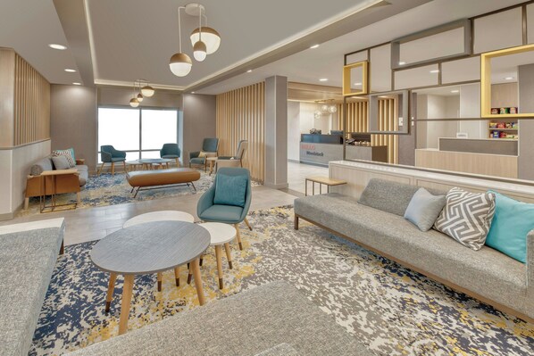 Un moderno vestíbulo de hotel con mostrador de recepción, zona de estar y un ventanal grande.