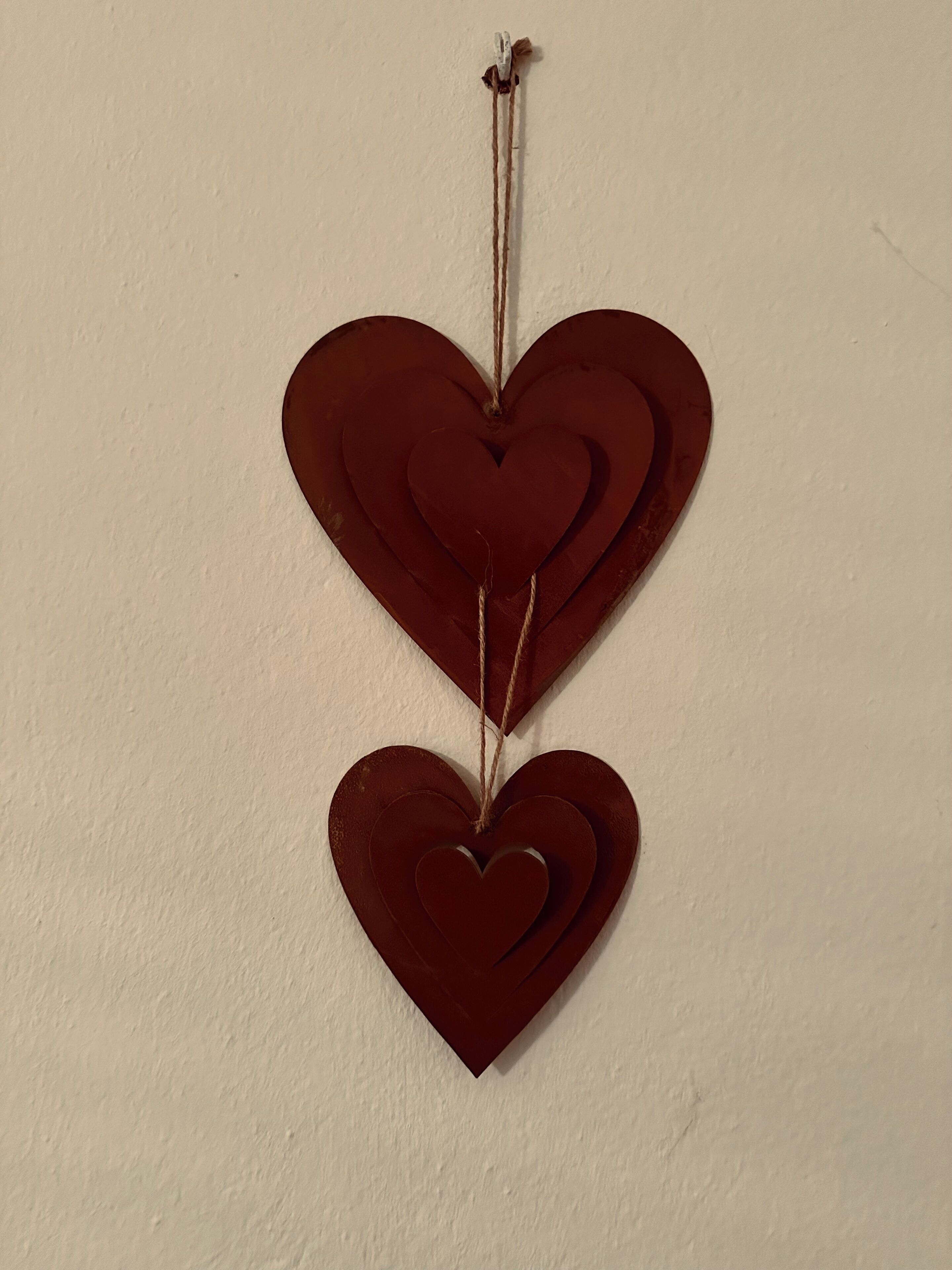 A wall-mounted heart-shaped decoration with a string.