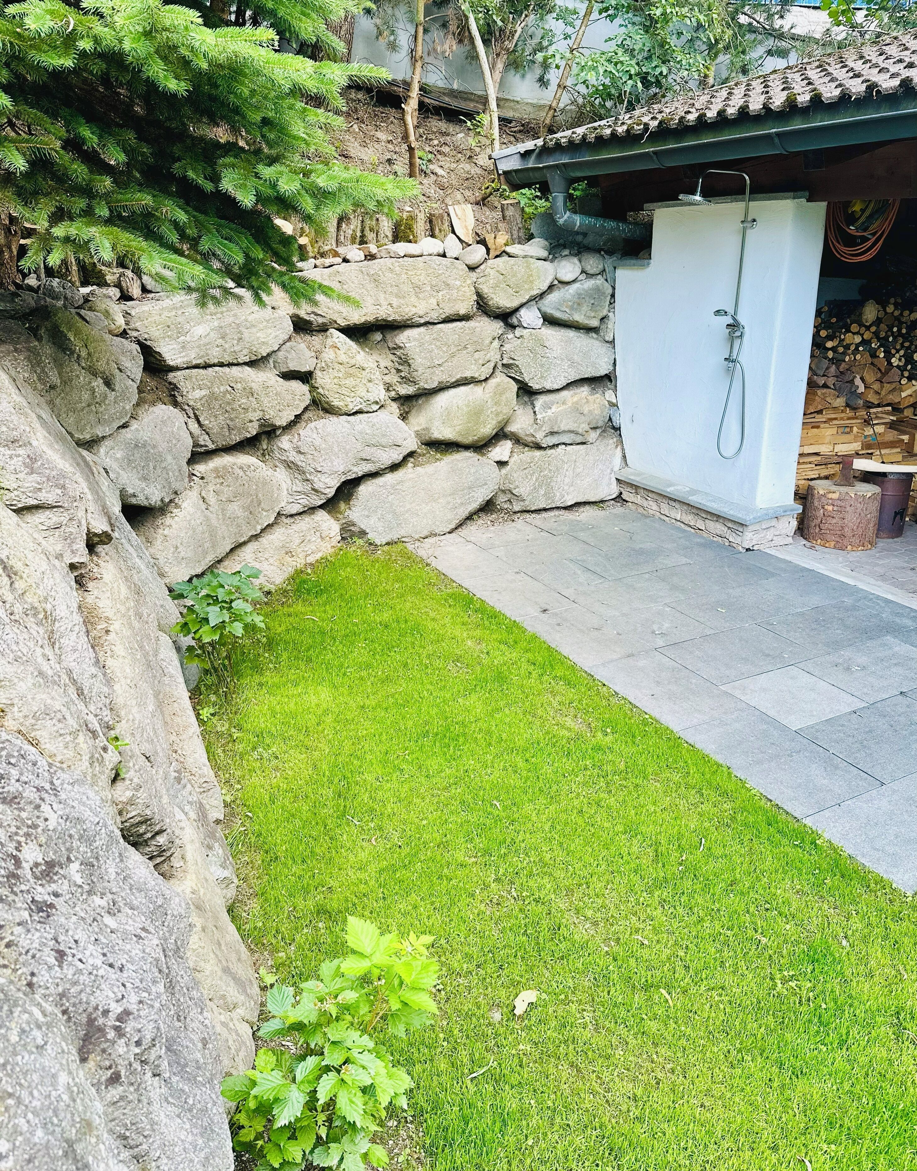 A stone wall, a grassy area, and a building with a tiled roof.