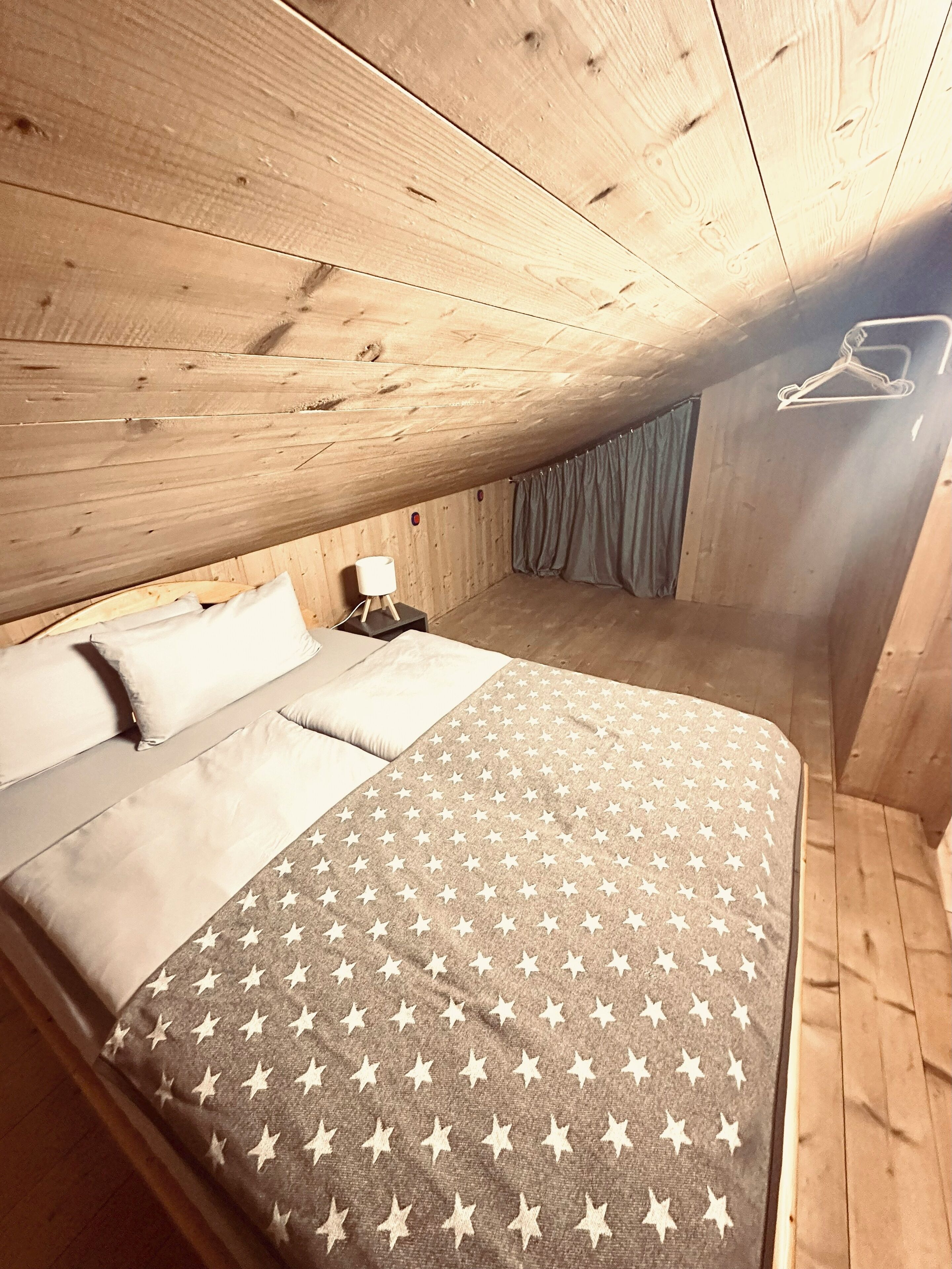A wooden-paneled room with a bed, a nightstand, and a hanging light.